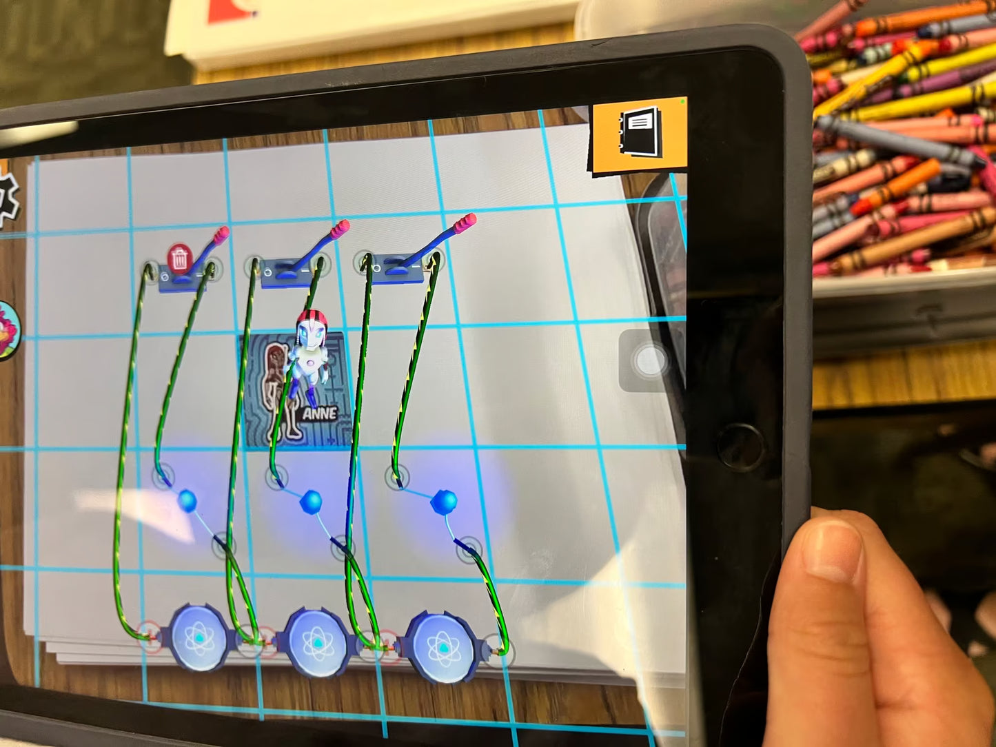 Person using a tablet with a coding or educational app displayed on the screen.