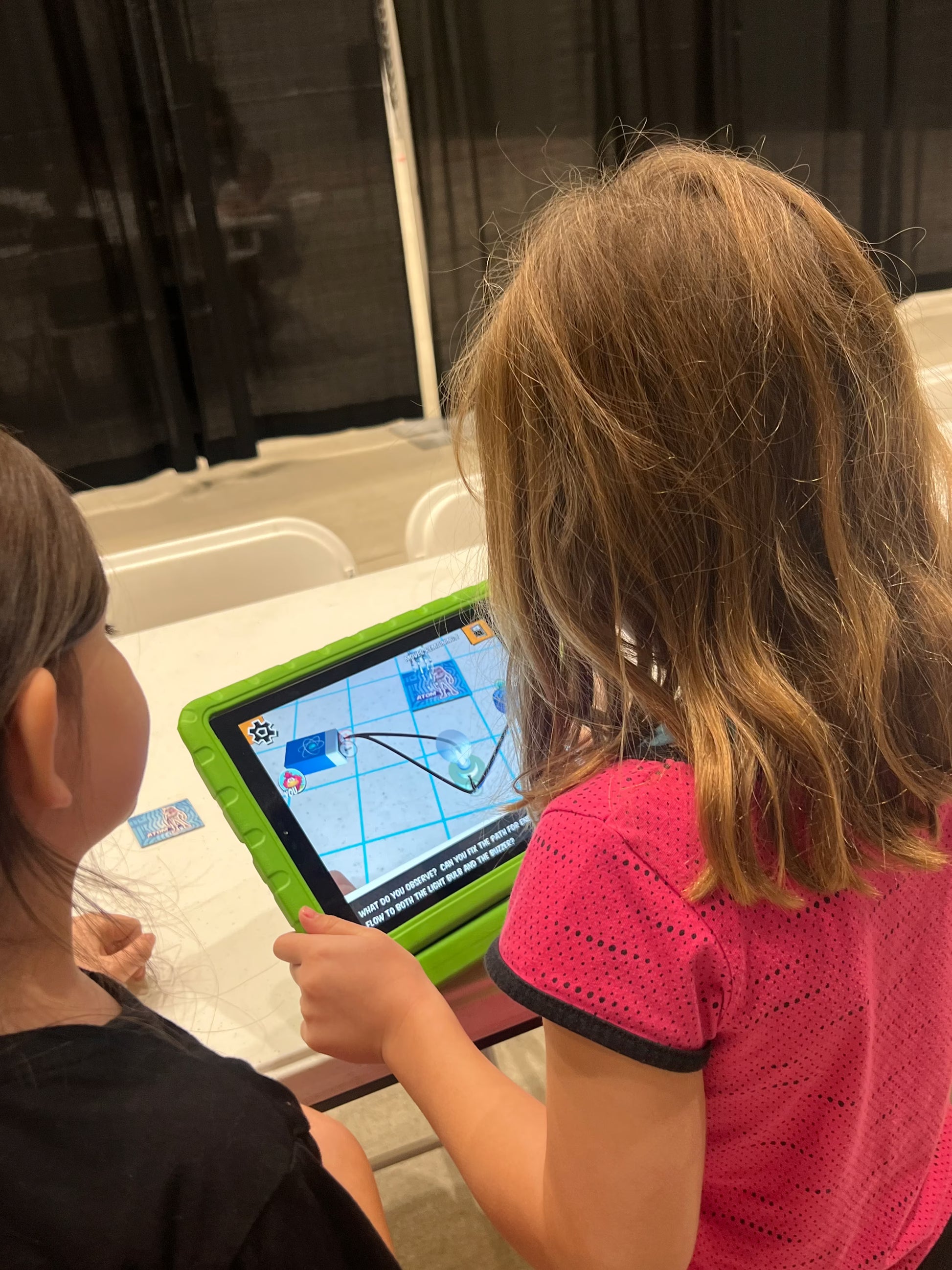 Two children looking at a tablet computer on a table.