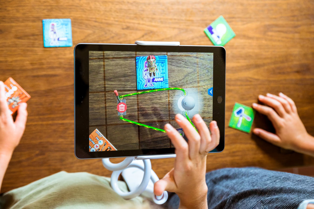 Children playing a augmented reality game on a tablet with cards on a wooden table.