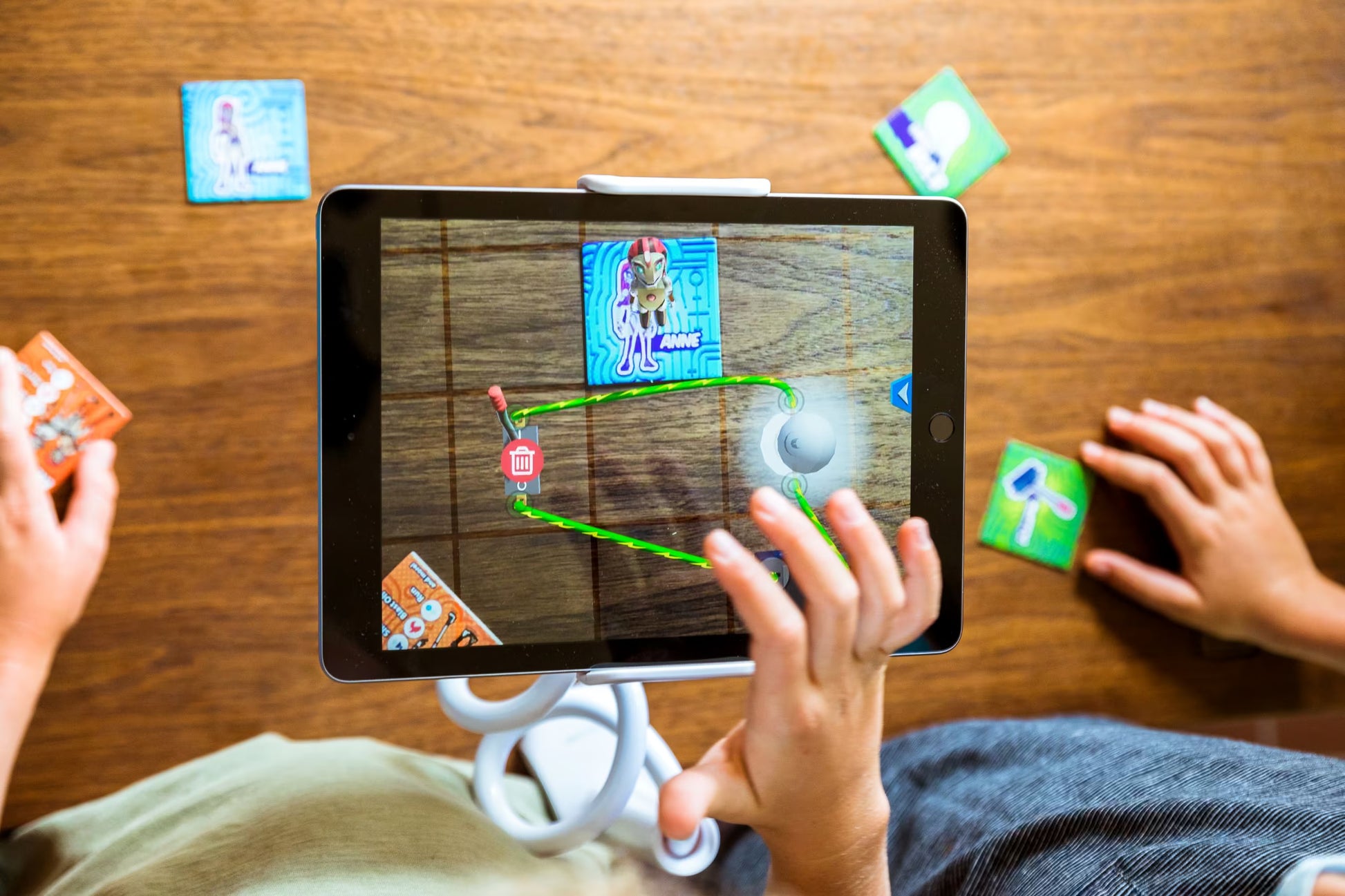 Children playing a augmented reality game on a tablet with cards on a wooden table.
