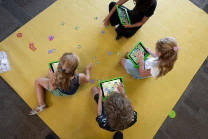 Four students sitting on a rug collaborating on a MindLabs project using tablets and augmented reality
