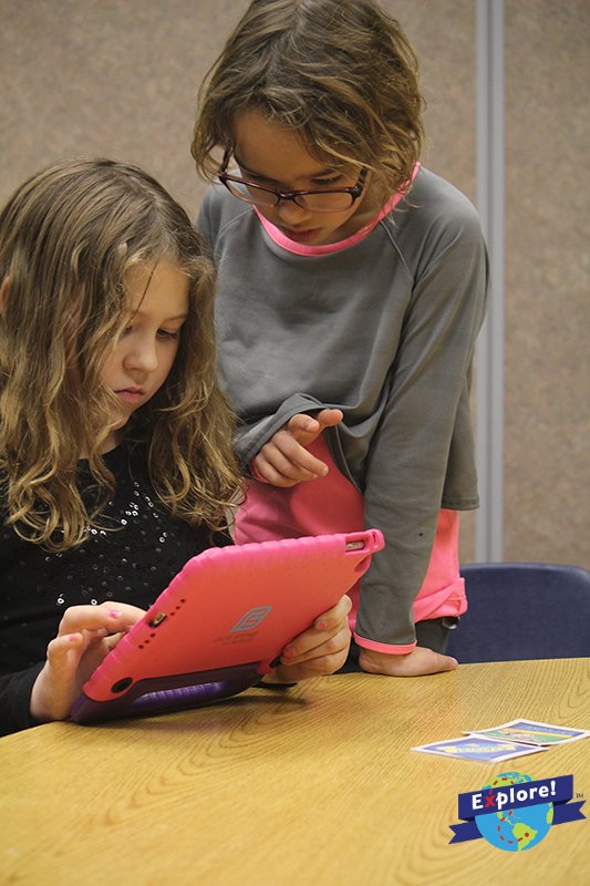 Two students play Explore Interactive's educational augmented reality mobile games.